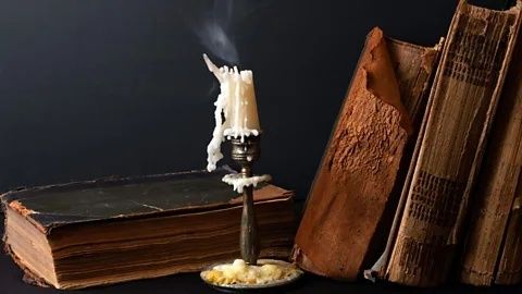 Alte Bücher und eine brennende Kerze als Sinnbild düsterer Poesie